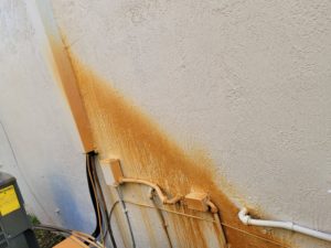 Alt text: Exterior wall showing extensive rust and mold staining before professional cleaning by Excelsior Power Cleaning