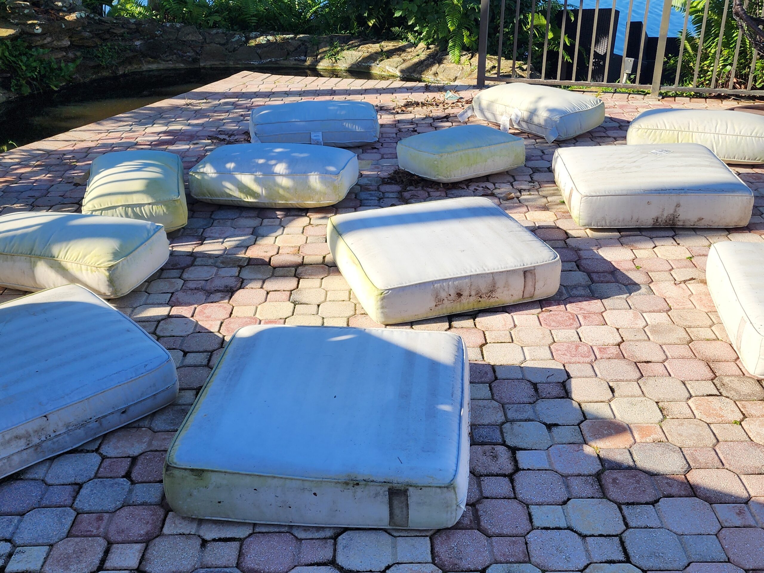 Outdoor cushions before restoration, showing heavy stains, mold, and discoloration