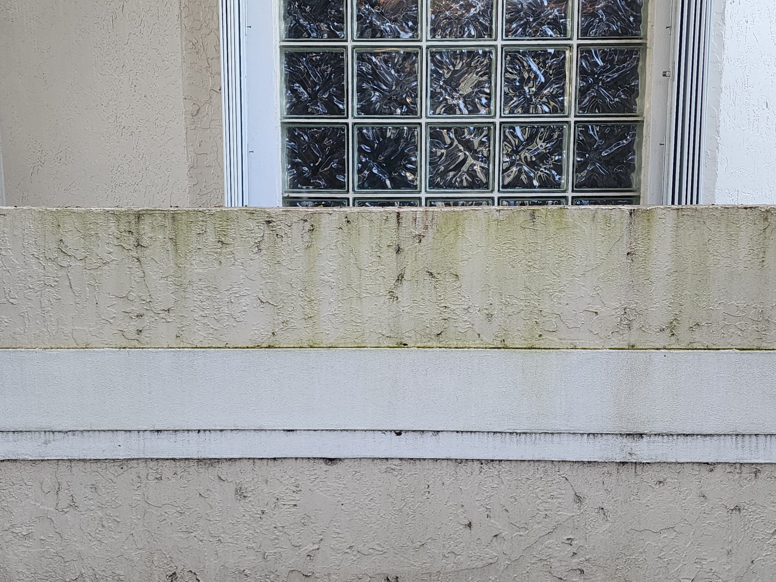 Before power cleaning of exterior walls in Boca Raton FL showing heavy dirt buildup, algae stains, and dark discoloration on residential wall surfaces